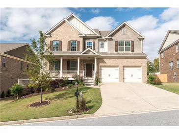 Inviting two-story brick home featuring a charming front porch and a two-car garage, complemented by a manicured lawn at 570 Eldridge Dr, Suwanee, GA 30024