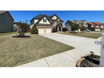 Two-story brick home features a two-car garage, landscaped yard, and a long concrete driveway at 2030 Hydrangea Ln, Austell, GA 30106
