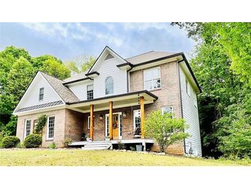 Charming two-story brick home with a welcoming front porch and lush landscaping at 2870 Willow Wisp Way, Cumming, GA 30040