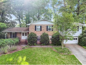 Charming two-story brick home featuring mature trees, a well-manicured lawn, and an attached two car garage at 3844 Lake Se Dr, Smyrna, GA 30082
