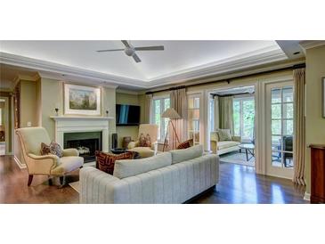 Bright living room featuring fireplace, hardwood floors, and doors leading to sunroom at 470 Ansley Walk Ne Ter, Atlanta, GA 30309