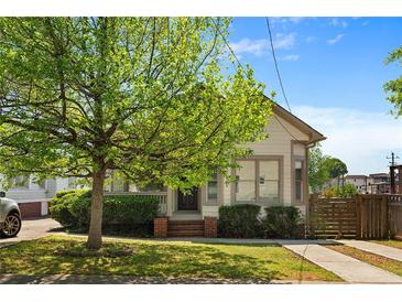 Charming home featuring a lush green lawn, mature tree, and inviting front porch at 77 Glenn Se St, Atlanta, GA 30312