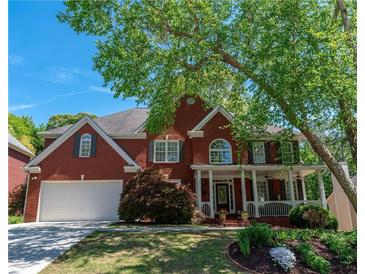Charming red brick home with a welcoming front porch and lush landscaping at 4035 Regal Oaks Dr, Suwanee, GA 30024