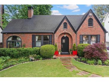 Charming brick Tudor-style home with manicured landscaping, arched entryway and a stone pathway at 557 E Wesley Ne Rd, Atlanta, GA 30305