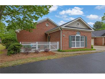 Charming brick home featuring a white picket fence and manicured landscaping at 509 Sawnee Corners Dr, Cumming, GA 30040