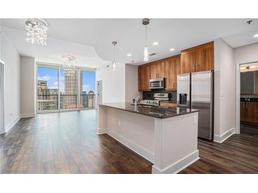 Modern kitchen featuring an island, stainless steel appliances, and dark hardwood floors, bathed in natural light and open to skyline views at 1080 Peachtree Ne St # 2515, Atlanta, GA 30309