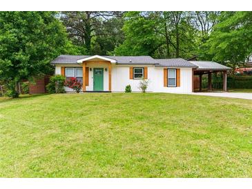 Charming home with a bright green front door and a covered carport, surrounded by a lush lawn at 2804 Hall Se Dr, Smyrna, GA 30082