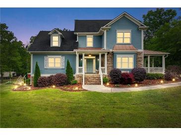 Charming two-story home with manicured lawn, stone accents and inviting front porch with beautiful landscaping at 65 Maude White Rd, Kingston, GA 30145