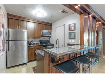 A cozy kitchen featuring stainless steel appliances, a breakfast bar, and wood cabinetry at 1150 Collier Nw Rd # K18, Atlanta, GA 30318