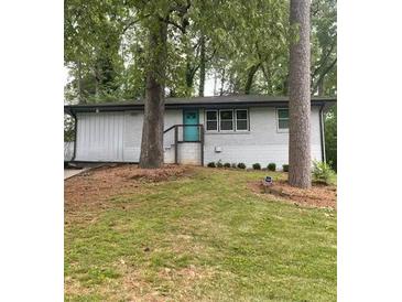 Charming single-story home featuring a turquoise front door, white painted brick, and lush green lawn at 2874 Cloverleaf Se Dr, Atlanta, GA 30316