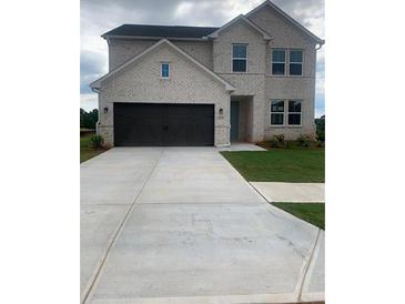 Two-story brick home featuring a dark garage door, neatly kept lawn and gray cloudy skies at 129 Kenney Way, Locust Grove, GA 30248