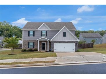 Charming two-story home with a brick and siding exterior, well-manicured lawn, and attached garage at 436 Vermeer Ct, Locust Grove, GA 30248