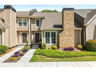 Charming townhome featuring a stone chimney, manicured lawn, and inviting walkway at 1420 Defoors Nw Dr, Atlanta, GA 30318