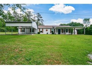 Charming single-story home with covered parking and a sprawling green lawn, perfect for outdoor activities at 7307 Banks Mill Rd, Douglasville, GA 30135