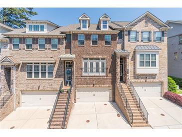 Attractive brick townhome featuring multi-car garage and brick staircase leading to the front entrance at 1382 Doublegate Ne Dr, Atlanta, GA 30319