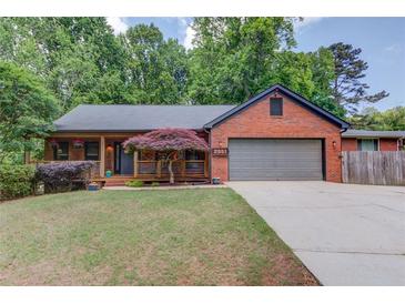 Charming brick home featuring a covered porch, manicured lawn, and attached garage at 2981 Cardinal Lake Dr, Duluth, GA 30096