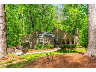 Charming home nestled among mature trees with a well-maintained lawn and inviting walkway to the front entrance at 3925 Rock Mill Pkwy, Marietta, GA 30062