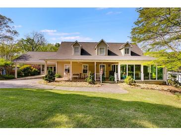 Charming tan home featuring a lush green lawn and a convenient covered carport at 317 Ellenwood Dr, Bowdon, GA 30108