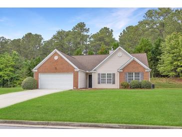 Charming one-story home with brick accents, a manicured lawn, and attached two-car garage at 1220 Skipping Rock Sw Ln, Grayson, GA 30017