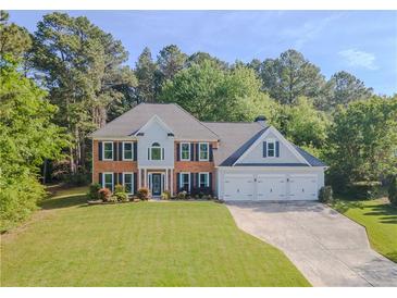 Charming two-story home boasts a manicured lawn and three-car garage, set amongst mature trees at 2478 Roseberry Ln, Grayson, GA 30017