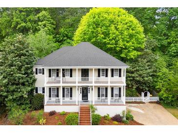 Charming two-story home featuring double porches, black shutters, and a lush, landscaped front yard with mature trees at 2870 Abbottswell Dr, Alpharetta, GA 30022