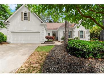 Charming home featuring a two-car garage, manicured lawn, and mature landscaping at 6250 Bannerhorn Run, Alpharetta, GA 30005