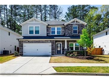 Charming two-story home with a stone and gray siding, well-manicured lawn, and a two-car garage at 660 Stately Dr, Woodstock, GA 30188