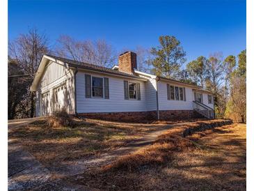 Charming home with a brick foundation, chimney, and an attached garage on a wooded lot at 11511 Highway 92, Woodstock, GA 30188