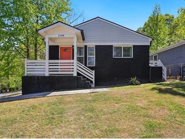Charming home boasts dark brick, a welcoming porch, and a vibrant orange door at 1599 Ezra Church Nw Dr, Atlanta, GA 30314