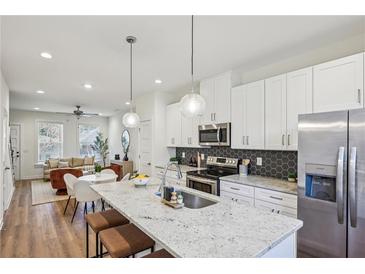 Modern kitchen with white cabinets, stainless steel appliances, and a large island with bar seating at 1095 Tucker Ave # 207, Atlanta, GA 30310