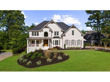 Stunning white painted brick two-story home with manicured lawn and beautiful landscape design at 7390 Canter Run, Cumming, GA 30040