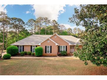 Charming brick ranch with well-manicured lawn, mature trees, and inviting front entrance at 1030 E Lakehaven Way, Mcdonough, GA 30253