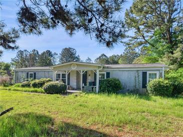 Charming single-story home with a cozy front porch and a well-manicured lawn surrounded by lush greenery at 1025 Rocky Plains Rd, Covington, GA 30016