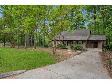 Charming home with a long driveway and a lush green yard surrounded by mature trees at 6693 Doublegate Ln, Rex, GA 30273
