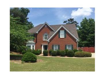 Charming brick two-story home with lush landscaping and a well-maintained lawn at 990 Lilac Arbor Rd, Dacula, GA 30019