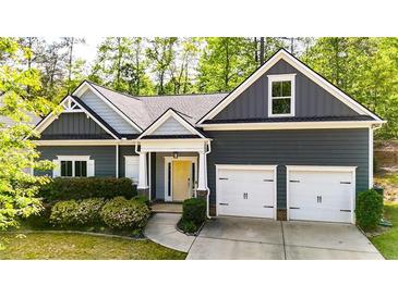 Charming home with a two-car garage, neat landscaping, and a welcoming yellow front door at 6859 Winding Wade Trl, Austell, GA 30168