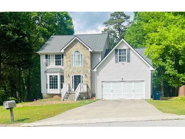 Charming two-story home with stone accents, well-maintained lawn, and attached two-car garage nestled on a wooded lot at 2317 Rocksram Ct, Buford, GA 30519