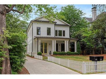 Charming two-story home with a inviting front porch, landscaped yard, and white picket fence at 357 Mell Ne Ave, Atlanta, GA 30307