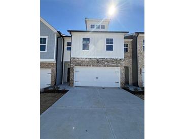 Exterior view of a townhome featuring a two-car garage, brick accents, and a contemporary design at 5641 Hislop Ln # 88, Mableton, GA 30126
