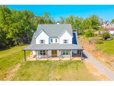 Stunning two-story home with a classic farmhouse design and welcoming front porch with rocking chairs at 5315 Hendrix Rd, Cumming, GA 30040