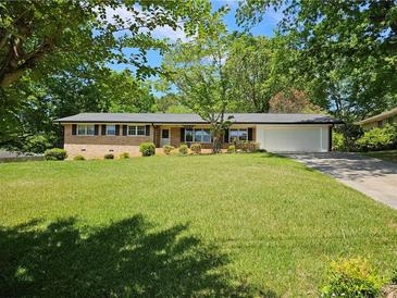 Charming brick home featuring a well-manicured lawn, mature trees, and a two-car garage at 4589 Mesaview Way, Stone Mountain, GA 30083