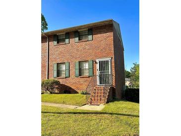 Charming brick townhome featuring well-maintained landscaping and a secure front entrance gate at 6354 Shannon Pkwy # 6F, Union City, GA 30291