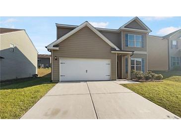 Inviting two-story home featuring a two-car garage and well-maintained lawn with blue shutters on the windows at 4428 Belcamp Rd, Fairburn, GA 30213