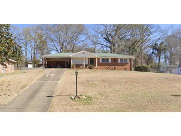 Cozy single-story brick home with a covered carport and a spacious front yard on a sunny day at 6073 Terry Ln, Austell, GA 30168