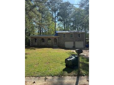 Charming single-Gathering home featuring brick facade, arched front windows, two-car garage, and a spacious front yard with mature trees at 1001 Woodbridge Ne Way, Conyers, GA 30012