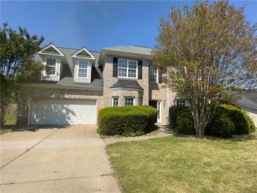 Traditional brick two-story home features a manicured lawn and attached two-car garage at 3835 Portico Run Dr, Buford, GA 30519
