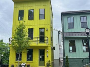 Three-story modern home with a lime green exterior and black accents, situated in a neighborhood at 968 Bibbs Circle Nw, Atlanta, GA 30318