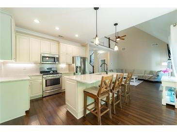 Eat-in kitchen features an island with bar seating, stainless appliances, and lovely pendant lighting at 2025 Goldmine Dr, Cumming, GA 30040