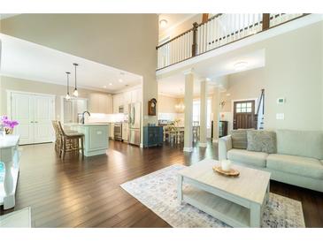 Bright open-concept living room with hardwood floors, high ceilings, and a modern kitchen in the background at 2025 Goldmine Dr, Cumming, GA 30040