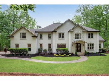 Stunning two-story home featuring a lush front lawn, manicured landscaping, and a charming stone and stucco facade at 1400 Squire Ln, Cumming, GA 30041